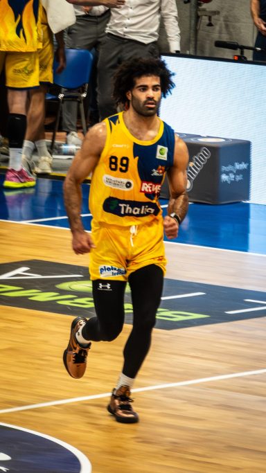 Basketballspieler in gelbem Trikot joggt auf dem Spielfeld.