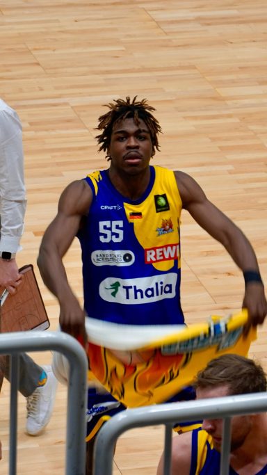 Ein Basketballspieler in Trikot hält ein Handtuch und schaut ins Publikum.