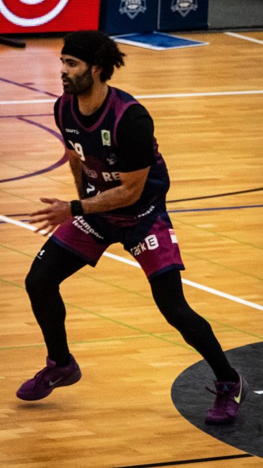 Basketballspieler in Aktion auf dem Spielfeld, bereit zum Passen oder Dribbeln.