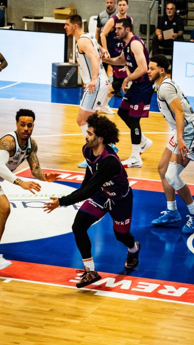 Basketballspiel mit Spielern in Aktion auf dem Spielfeld.